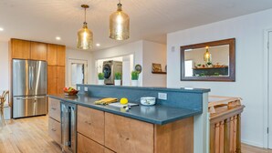 Une cuisine moderne avec des meubles en bois, des appareils électroménagers en acier inoxydable et des luminaires suspendus.