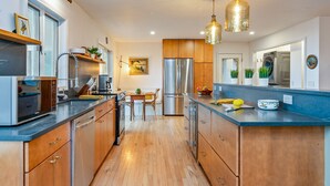 Une cuisine moderne avec des meubles en bois, des appareils en acier inoxydable et des luminaires suspendus.