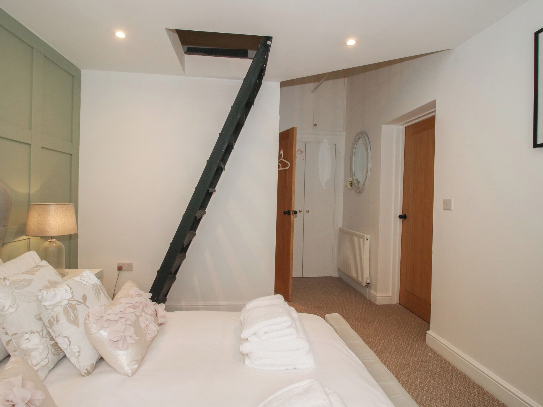 A bedroom with a bed, pillows, a lamp, and a radiator.
