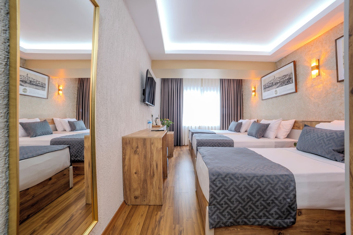 A hotel room with two beds, a wooden desk, and a large mirror.