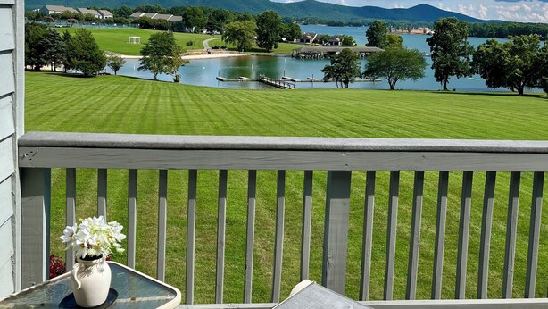 Un balcon offrant une vue sur un lac, des prairies et des montagnes lointaines.