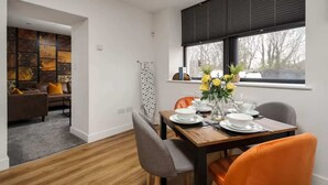 Un coin repas avec une table dressée pour quatre personnes, un canapé et une vue sur l’extérieur.