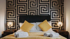 Un lit avec une tête de lit à motifs géométriques, deux lampes de chevet et un plaid jaune.