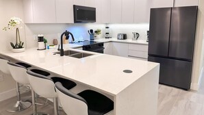 A modern kitchen with a central island, stainless steel appliances, and white cabinetry.