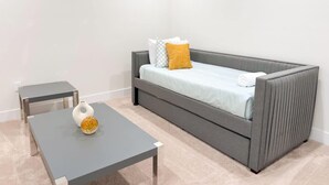 A modern, minimalist room with a grey sofa, a small table, and a decorative vase.