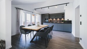 Een moderne keuken met een centraal eiland, donker houten vloeren en een eetgedeelte met een houten tafel en stoelen.