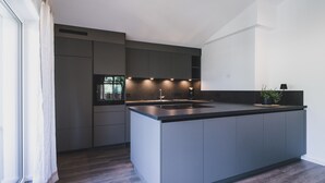 Een moderne keuken met een centraal eiland, inbouwapparatuur en uitzicht op het omliggende landschap.