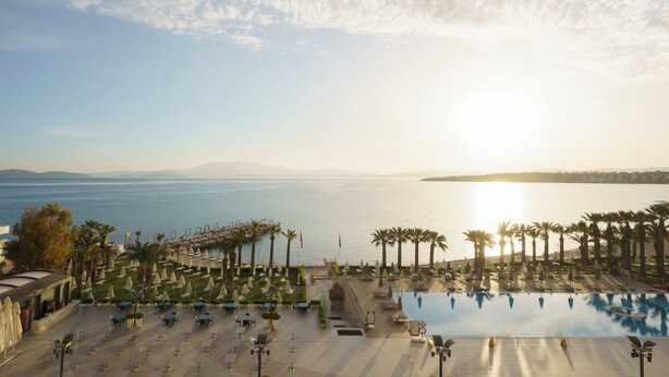 A resort with a pool, palm trees, and a view of the sea. - Boyalık Beach Palms Hotel (Cesme)