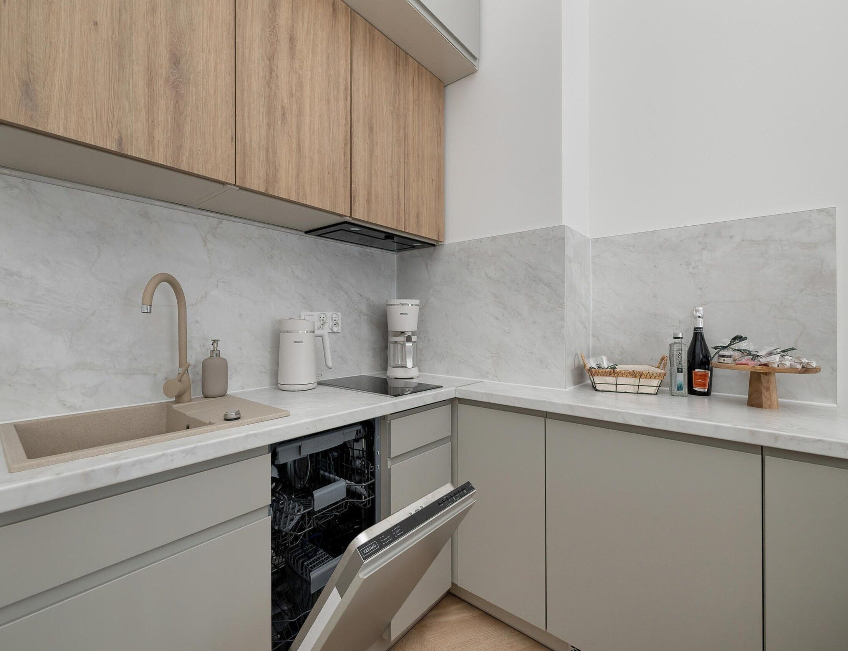 Cocina moderna con lavavajillas integrado, cafetera y una botella de vino sobre la encimera.