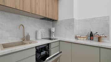 Cocina moderna con lavavajillas integrado, cafetera y una botella de vino sobre la encimera.