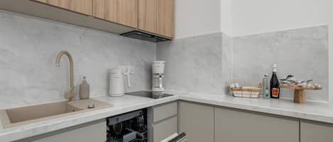 A modern kitchen with a built-in dishwasher, a coffee maker, and a wine bottle on the counter.