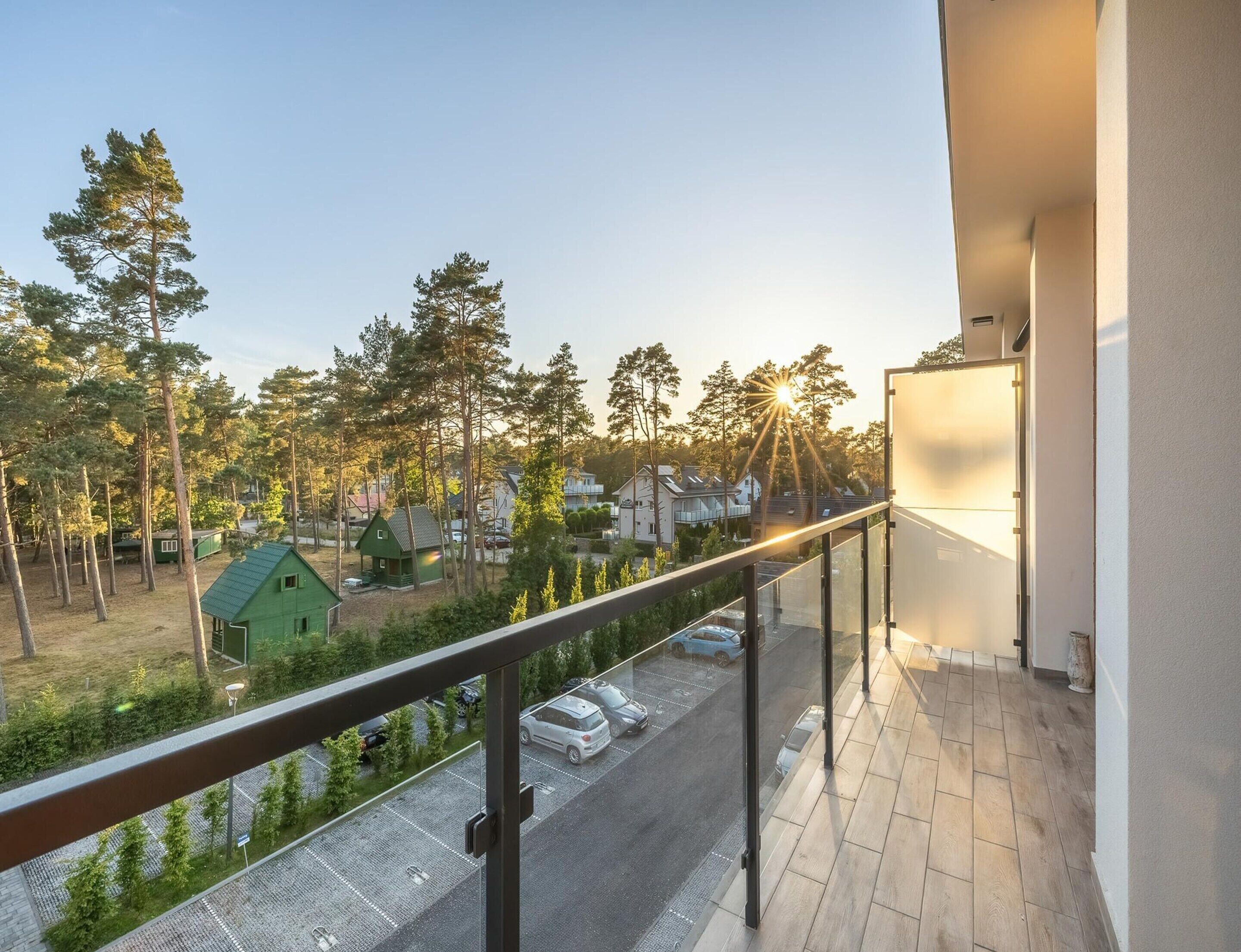 Un balcone con vista su una zona residenziale, un parcheggio e una casa con giardino.