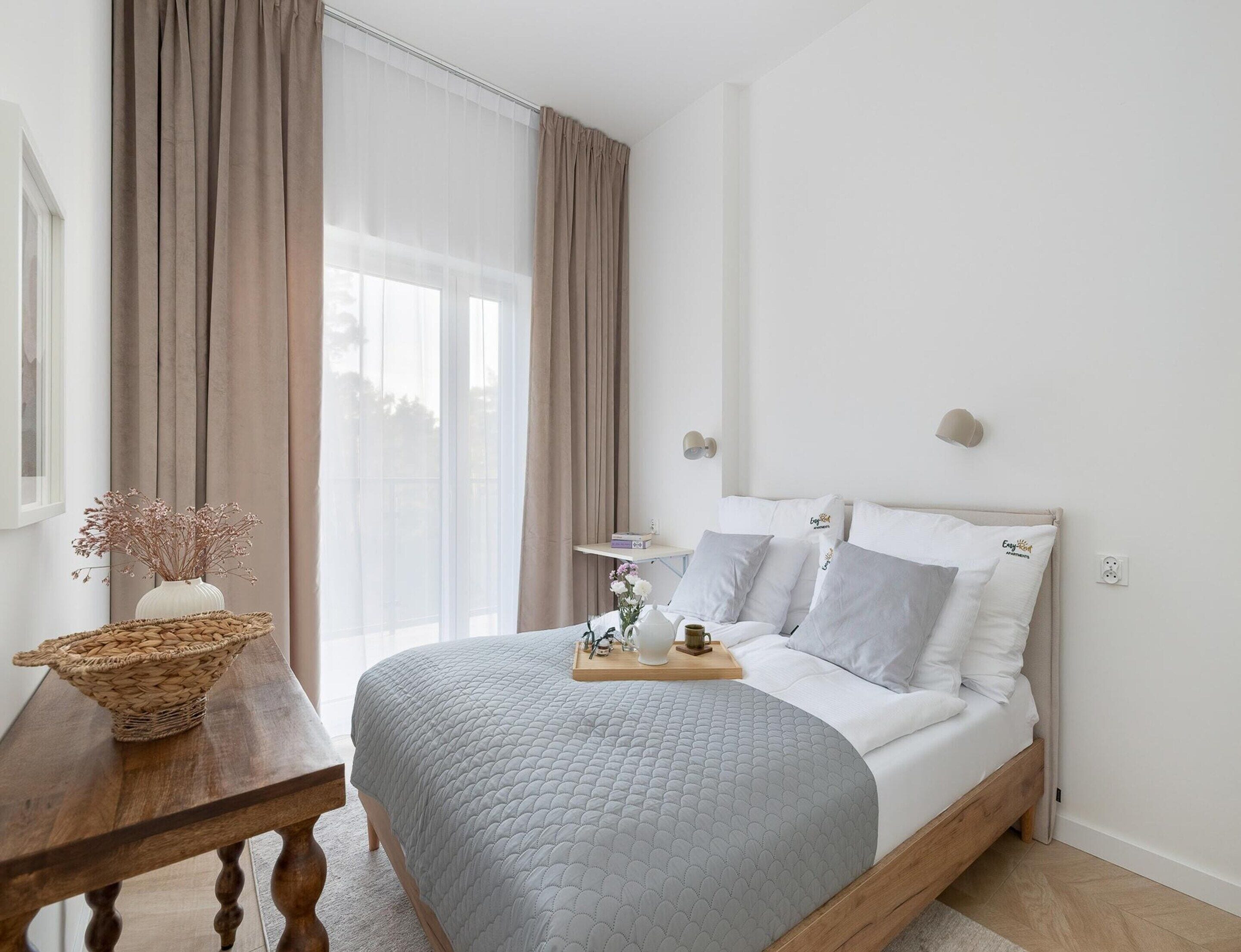 A bedroom with a bed, bedside table, and a window with curtains.