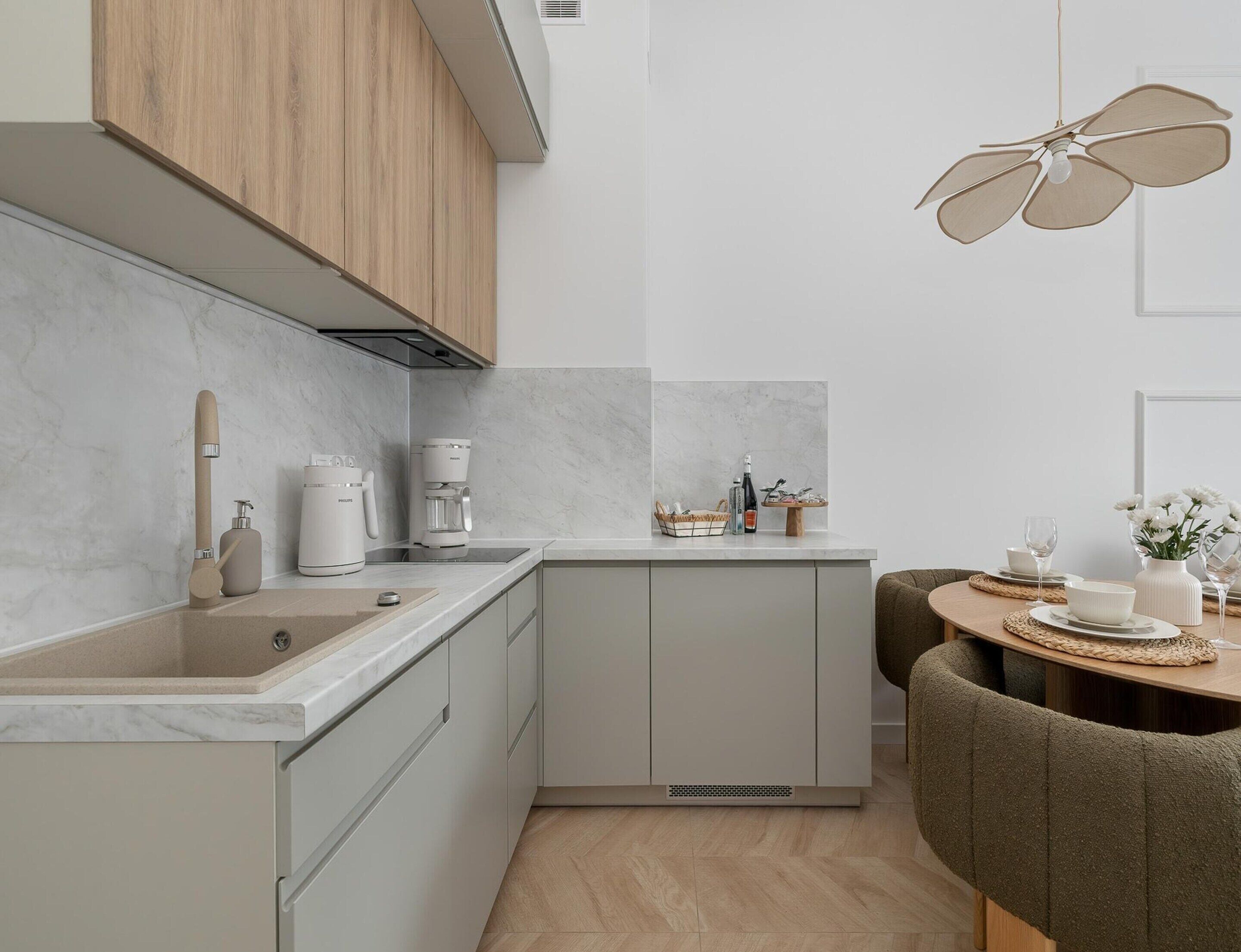 Una cocina moderna con encimera de mármol, una cafetera y un comedor con mesa redonda y sillas.