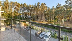 A modern building with a glass balcony overlooking a parking area and a forested area. - Apartment, Indoor Pool, Close to the Beach (Rewal)