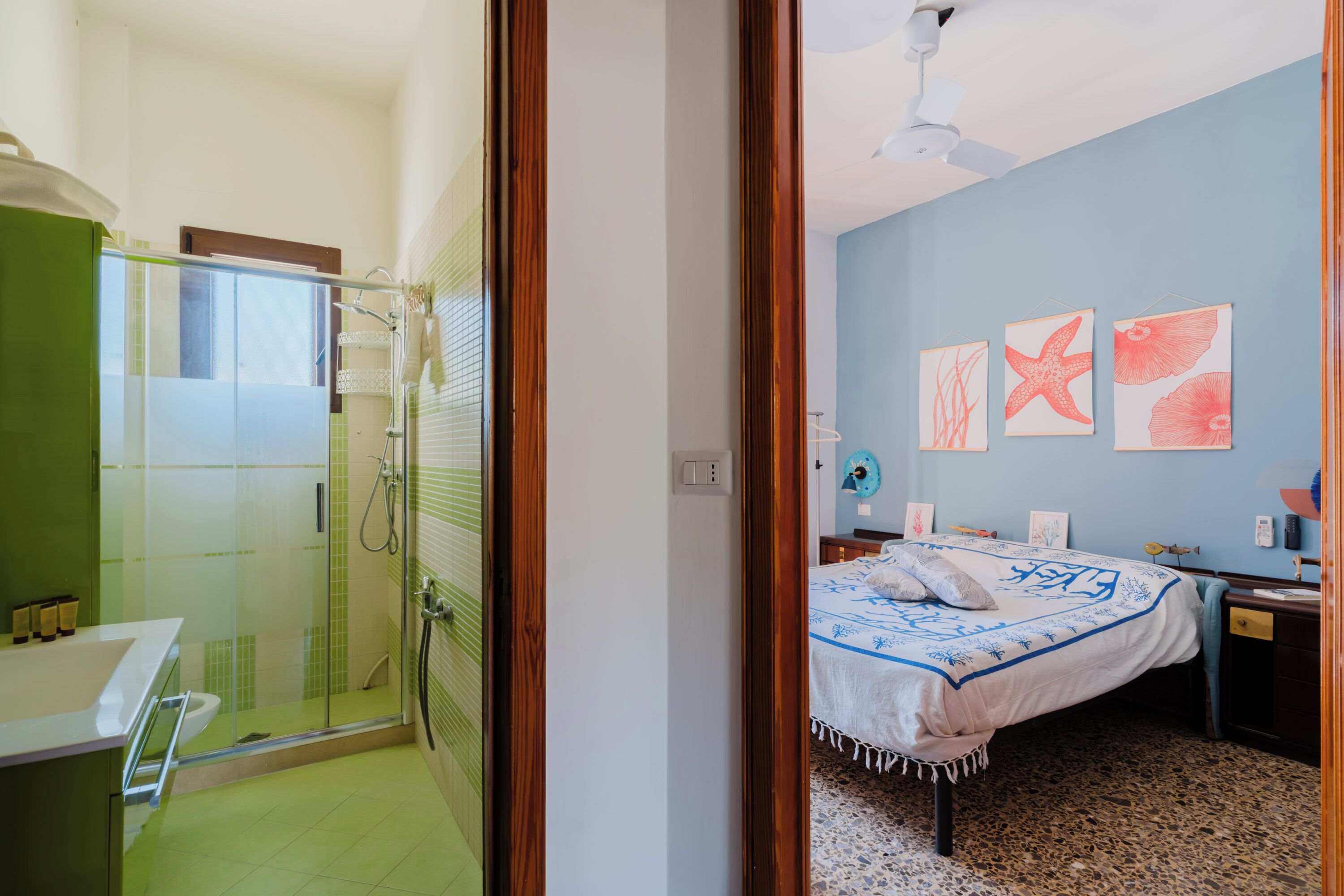 Un dormitorio con cama, mesita de noche, cómoda y una pared decorada con tres cuadros.