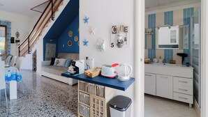 Una sala de estar moderna con una escalera, una cocina con azulejos azules y un comedor con alfombra estampada.