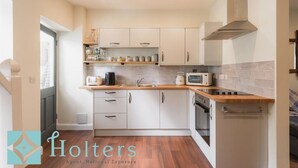 A modern kitchen with white cabinets, a wooden countertop, and a built-in microwave.