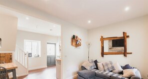 A living room with a grey sofa, wooden shelves, and a fireplace.