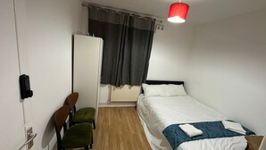 A small, clean room with a single bed, a chair, a desk, and a radiator. - Comfortable Budget Room with Shared Bathroom in East London 2 (London)