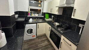A compact kitchen with a washing machine, oven, and a window above the sink. - Comfortable Budget Room with Shared Bathroom in East London 2 (London)