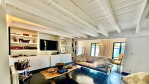 A modern living room with a sofa, coffee table, and shelves with various items. - Spectacular4-bedroom Villa- Private Pool, Sea Views and TropicalGardens. (Menton)