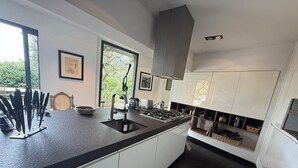 A modern kitchen with white cabinets, a black countertop, and a large window. - Spectacular4-bedroom Villa- Private Pool, Sea Views and TropicalGardens. (Menton)