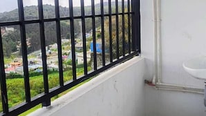 Un baño pequeño con ventana, un lavabo blanco y vistas a un paisaje verde.