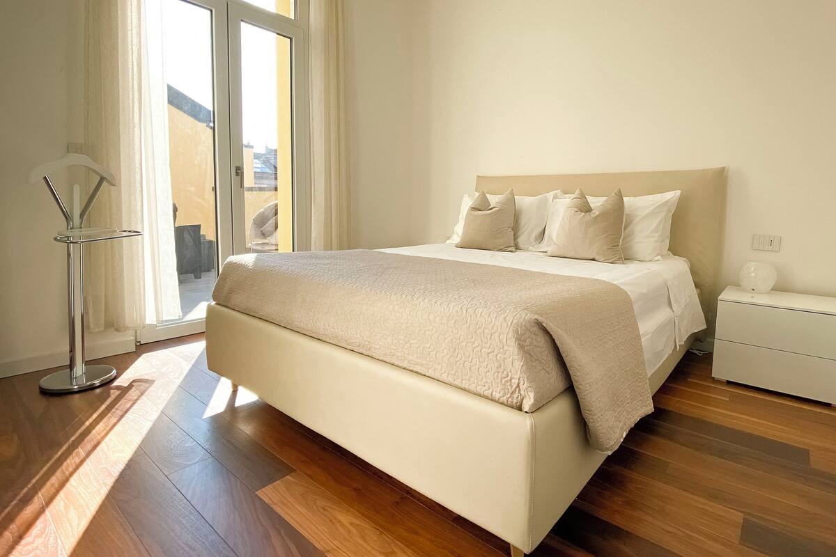 A bedroom with a bed, bedside table, and a floor lamp.