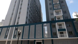 Un edificio moderno de rascacielos con varios pisos, ventanas amplias y una entrada destacada con un letrero.