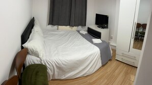 A hotel room with a bed, a TV, a small desk, and a mirror. - Comfortable Budget Ensuite Room in East London 3 (London)