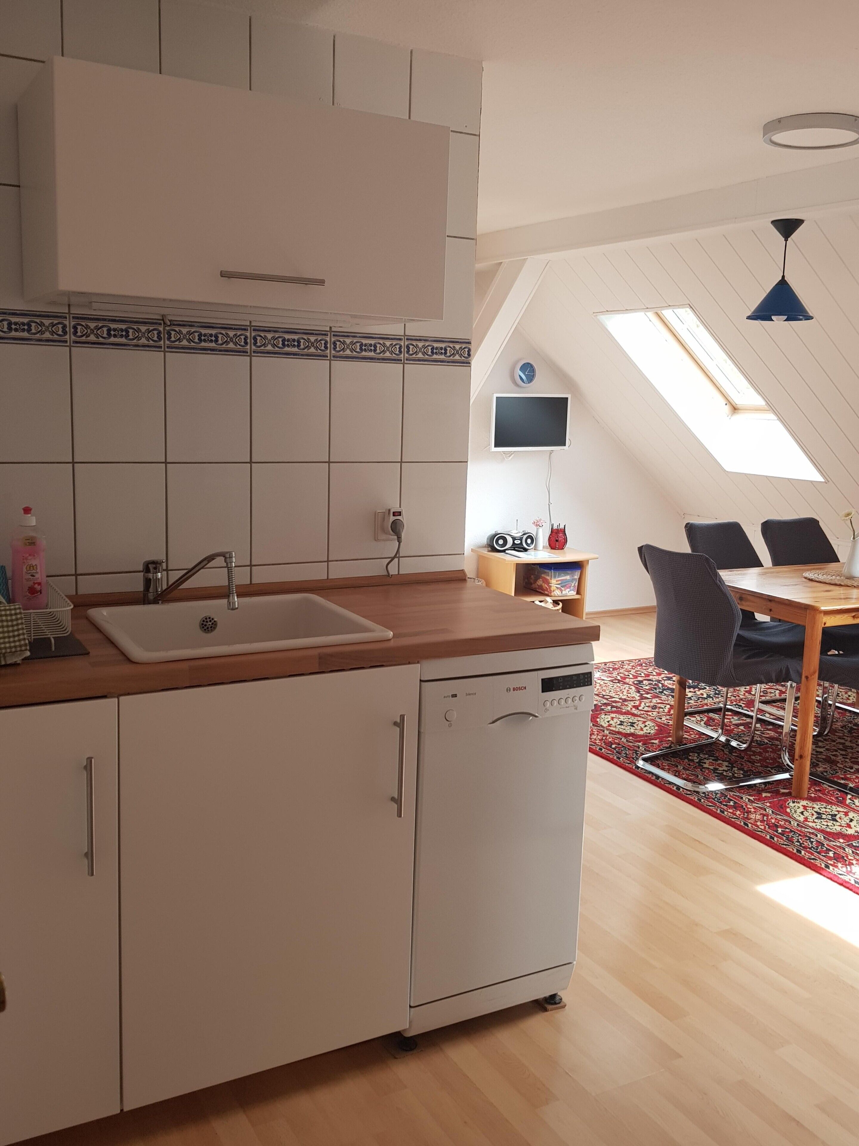 Una cocina con lavavajillas, fregadero y encimera de madera.