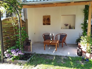An outdoor patio with a table and chairs, a wooden trellis, and potted plants. - Holiday Apartment 'Wolf' with Private Terrace, Shared Garden & Wi-Fi (Nietwerder)
