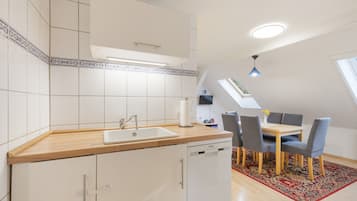 Eine kleine Küche mit Spüle, Holzarbeitsplatte und Essbereich mit Tisch und Stühlen.