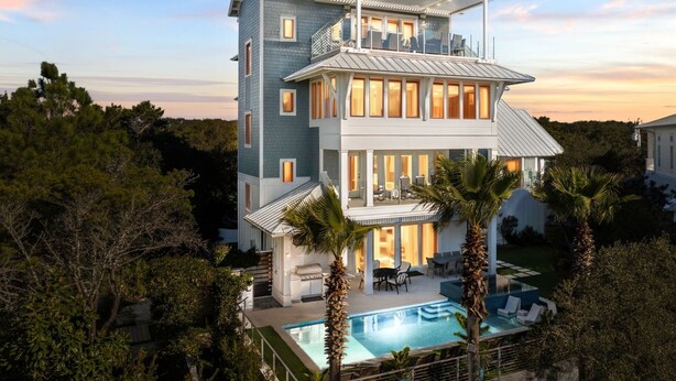 A multi-story house with a pool, surrounded by trees.