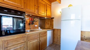 A kitchen with wooden cabinets, a built-in oven, a dishwasher, and a refrigerator. - Duplex Jouve with Exceptional View (Saint-Véran)