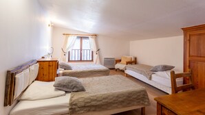 A room with two beds, a wooden table, a desk, a chair, and a window with curtains. - Duplex Jouve with Exceptional View (Saint-Véran)