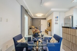 Una sala de estar moderna con una mesa de centro de vidrio, sofás azules y un jarrón decorativo.