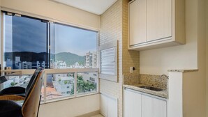 A modern kitchen with a large window, white cabinets, and a granite countertop. - Apt w/ BBQ Garage 550m From Beach Zuc0703 (Balneário Camboriú)