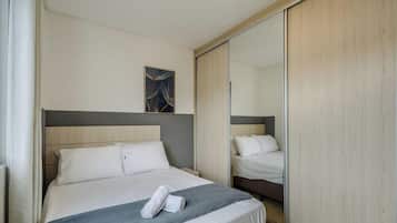 A hotel room with a bed, a mirror, and a painting on the wall.