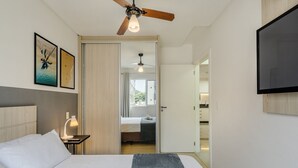 A hotel room with a bed, a ceiling fan, a TV, and artwork on the wall. - Apt w/ BBQ Garage 550m From Beach Zuc0703 (Balneário Camboriú)