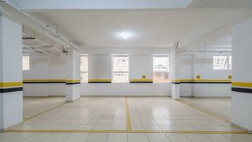 Um espaço amplo e bem iluminado, com piso de azulejos e paredes brancas, com faixas amarelas e pretas nas bordas.