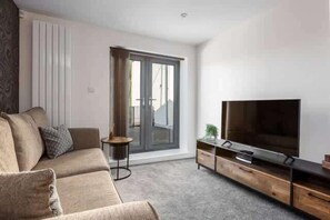 A modern living room with a sofa, TV, and sliding glass door.