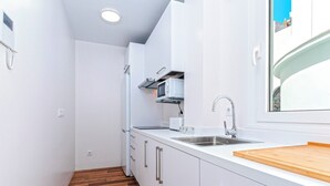 A compact kitchen with white cabinets, a wooden countertop, a built-in microwave, and a stainless steel sink. - Lovely Apartment in the Center. San Antonio III (Cádiz)