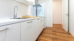 A modern kitchen with white cabinets, a stainless steel sink, and a wooden countertop. - Luxury Apartment in Cadiz Center. San Antonio IV (Cádiz)