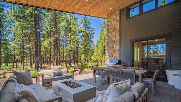 Un patio al aire libre con un brasero, asientos y vistas a un bosque.