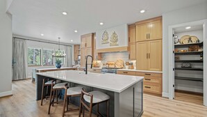 Cocina moderna con una isla grande, armarios de madera y vistas al exterior.