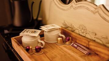 A tray with two white cups, two gold cups, and a chocolate bar on a wooden tray.