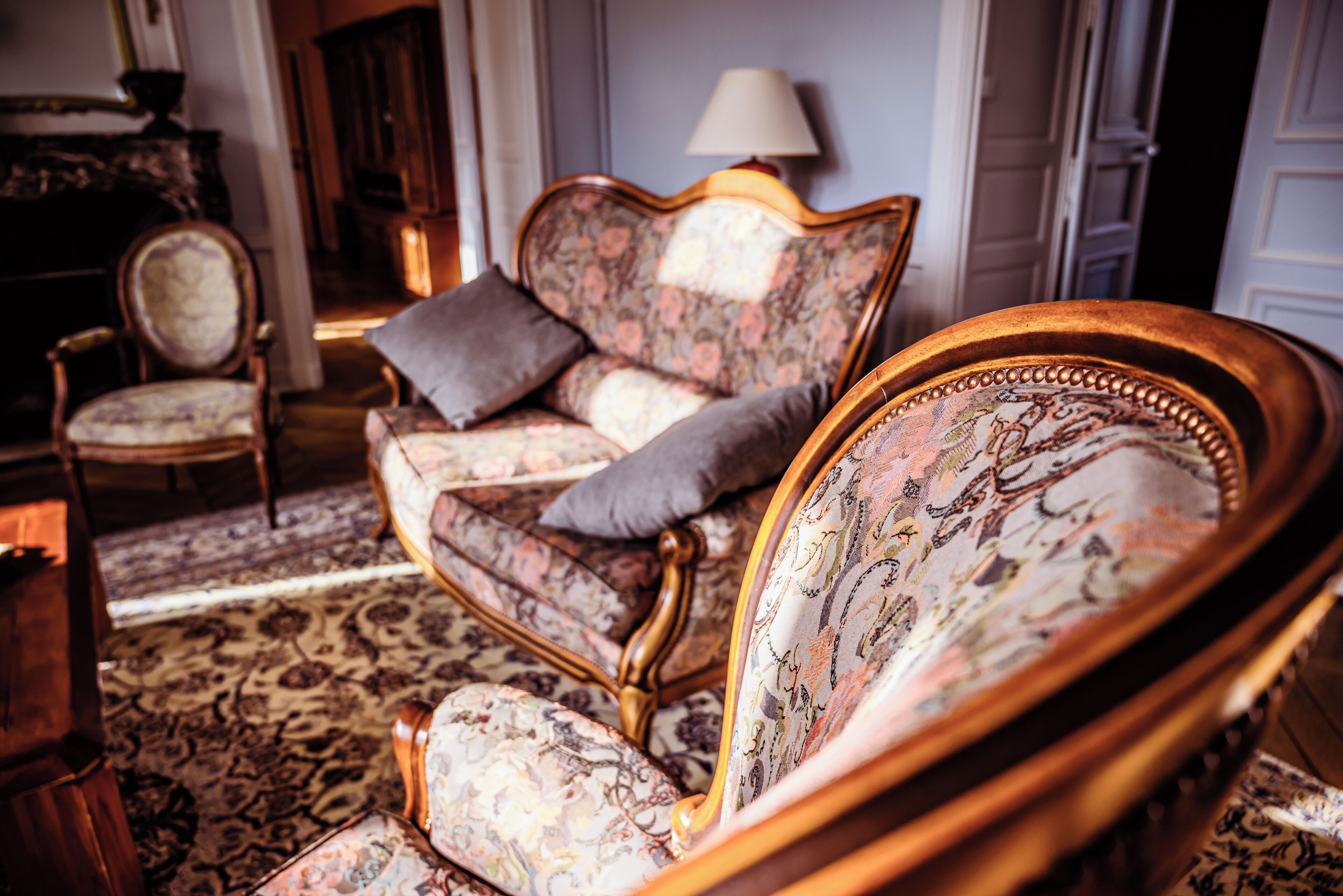 A traditional room with a floral patterned sofa, a matching armchair, and a classic wooden side table.