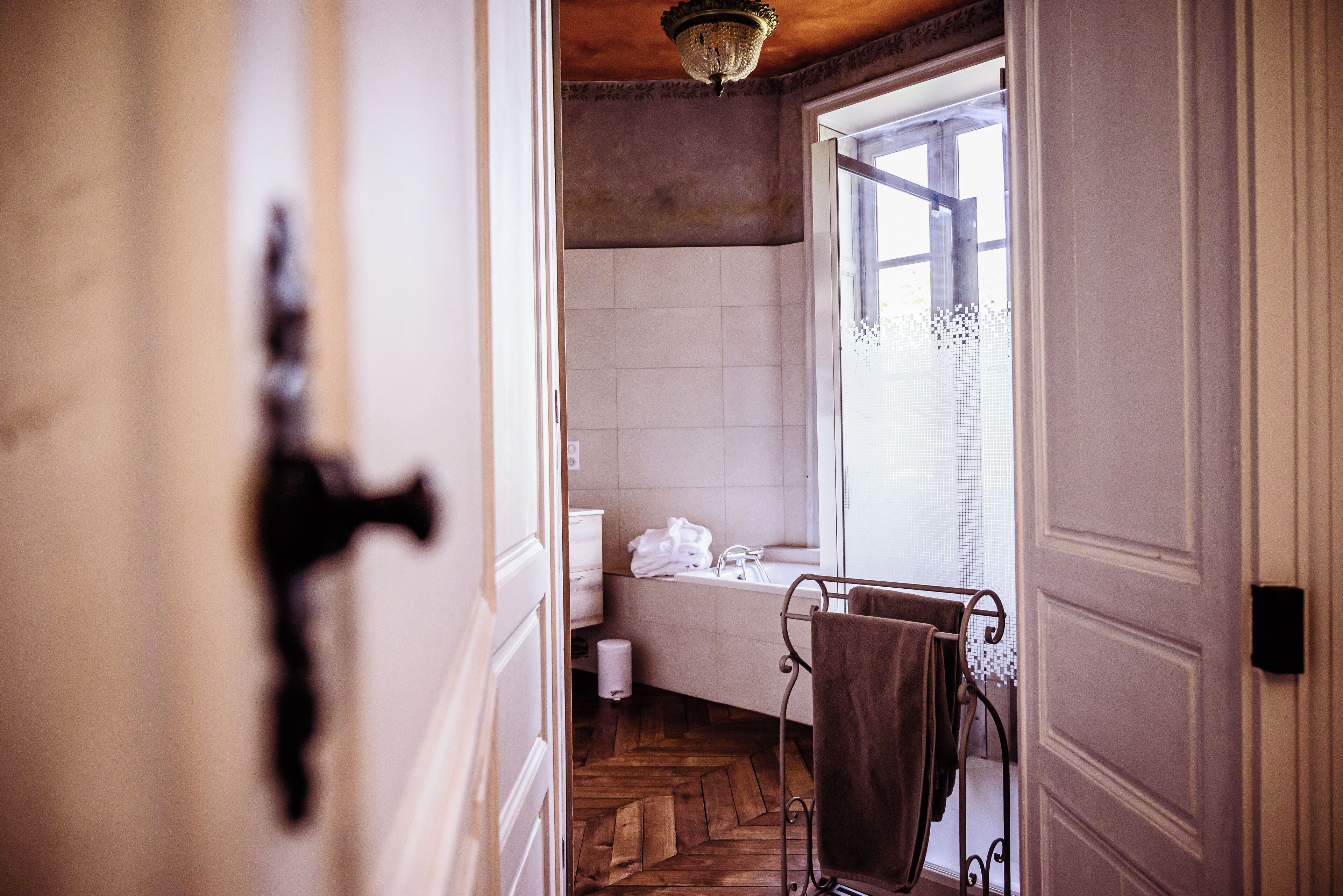 A bathroom with a wooden floor, a bathtub, and a towel rack.